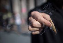 A man holds a joint while smoking marijuana, in Vancouver on Wednesday Oct. 17, 2018. British Columbia has released the results of its public engagement to help inform the government's decision on allowing spaces for consuming cannabis.THE CANADIAN PRESS/Darryl Dyck
