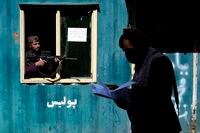 A Taliban fighter stands guard as a man enters the government passport office, in Kabul, Afghanistan, Wednesday, April 27, 2022. (AP Photo/Ebrahim Noroozi)