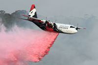 (FILES) This file photo taken on January 10, 2020 shows a C-130 Hercules plane from the New South Wales Rural Fire Service dropping fire retardent to protect a property during an operation to douse bushfires in Penrose, in Australia's New South Wales state.