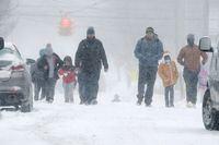 Parents and children walk north on German Street after school in Erie, Pa., Thursday, Feb. 3, 2022. Most sidewalks are packed with snow already, making it difficult for anyone trying to navigate on foot. A strong winter storm brought heavy winds and snow across the northeast U.S.(Greg Wohlford/Erie Times-News via AP)