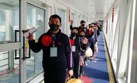 A screen grab from the China Civil Aviation Network site of transferred workers as they queue to board a plane in 2020 dressed in matching attire and with red flowers pinned to their chests.