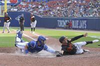 Baltimore Orioles’ Stevie Wilkerson (12) evades a tag by Toronto Blue Jays catcher Reese McGuire and slides across home safely on a single by Pedro Severino during the seventh inning of a baseball game in Buffalo, N.Y., Saturday, June 26, 2021. (AP Photo/Joshua Bessex) 