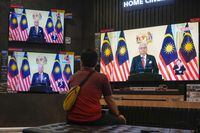 A customer watches a live broadcast of an announcement by Malaysian Prime Minister Ismail Sabri Yaakob at an electronics store in Kuala Lumpur, Monday, Oct. 10, 2022. Ismail announced Monday that Parliament will be dissolved, paving the way for general elections. (AP Photo/Vincent Thian)