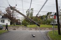 A snapped power pole hangs over a street in New Glasgow, N.S. on Wednesday, September 28, 2022 following significant damage brought by post tropical storm Fiona. THE CANADIAN PRESS/Darren Calabrese