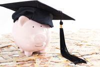 Piggy bank with graduation cap and large amount of canadian one hundred dollar bills, education savings/financial concept.