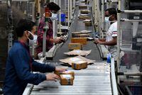 FILE PHOTO: Workers at Flipkart, a leading e-commerce firm in India, sort packets on a conveyor belt inside its fulfilment centre on the outskirts of Bengaluru, India, September 23, 2021. REUTERS/Samuel Rajkumar/File Photo