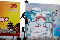 Workers put up government propaganda to fight against the COVID-19 outbreak, in Beijing, on Feb. 20, 2020.