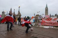 People wrapped in Canadian flags plays soccer in front of Parliament Hill, as truckers and supporters continue to protest coronavirus disease (COVID-19) vaccine mandates, in Ottawa, Ontario, Canada, February 9, 2022. REUTERS/Lars Hagberg