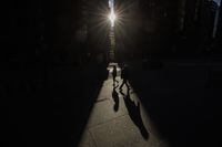 A new BMO report suggests excess household savings in Canada and the U.S. may help both countries avoid a severe economic downturn amid high interest rates. Pedestrians walk through a sliver of sunlight in the financial district in downtown Toronto on Wednesday July 6, 2022. THE CANADIAN PRESS/Cole Burston
