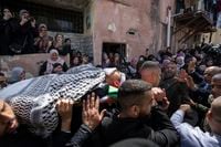 Palestinian mourners carry the body of Sanad Abu Atiyeh, 17 into the family house, during his funeral in the West Bank refugee camp of Jenin, Jenin, Thursday, March 31, 2022. Israeli forces raided a refugee camp in the occupied West Bank early Thursday, setting off a gun battle in which two Palestinians were killed and 15 were wounded, the Palestinian Health Ministry said. (AP Photo/Nasser Nasser)
