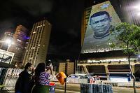 A woman takes a photo of the image of late soccer player Pele, reproduced on the building of the Federation of Industries of Sao Paulo, in Sao Paulo, Brazil, Thursday, Dec. 29, 2022. Pele, who played most of his career with Santos FC, has died in Sao Paulo. (AP Photo/Marcelo Chello)