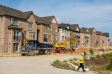 FILE PHOTO: A construction crew walks in front of new homes under construction, on the day Bank of Canada increased its policy rate a full percentage point in Brampton, Ontario, Canada July 13, 2022. REUTERS/Carlos Osorio/File Photo