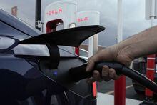 FILE - A motorist charges his electric vehicle at a Tesla Supercharger station in Detroit, Wednesday, Nov. 16, 2022. About half of U.S. adults say they are not likely to go electric when it comes time to buy a new vehicle, a new poll by The Associated Press-NORC Center for Public Affairs Research and the Energy Policy Institute at the University of Chicago shows. (AP Photo/Paul Sancya, File)
