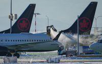 An Air Canada aircraft is de-iced at Vancouver International Airport in Richmond, B.C., Wednesday, Dec. 21, 2022. The Greater Saskatoon Chamber of Commerce is asking the the federal competition regulator to investigate Air Canada's decision to end its flights between Saskatoon and Calgary and between Regina and Calgary. THE CANADIAN PRESS/Darryl Dyck