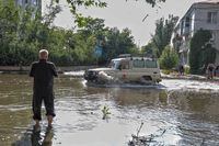 Red Cross volunteers drive a car on a flooded street after the Nova Kakhovka dam was destroyed in Kherson, Ukraine.
