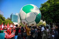 People crowd the street to watch a giant football being rolled out in a "Trophy Experience" event in Surabaya on October 29, 2023, ahead of the start of the FIFA U-17 World Cup Indonesia 2023 football tournanment. (Photo by JUNI KRISWANTO / AFP) (Photo by JUNI KRISWANTO/AFP via Getty Images)