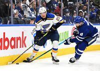 Feb 19, 2022; Toronto, Ontario, CAN;  St. Louis Blues forward Jordan Kyrou (25) moves the puck away from Toronto Maple Leafs defenseman Jake Muzzin (8) in the second period at Scotiabank Arena. Mandatory Credit: Dan Hamilton-USA TODAY Sports