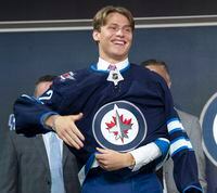 Winnipeg Jets Rutger McGroaty puts on his jersey during the first round of the 2022 NHL Draft   Thursday, July 7, 2022 in Montreal. THE CANADIAN PRESS/Ryan Remiorz