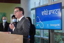 B.C. Health Minister Adrian Dix speaks during an announcement about the expansion of a program that assists internationally educated doctors in obtaining a licence to practice in the province, as "more doctors" is displayed on a screen in Hindi, in Richmond, B.C., on Sunday, November 27, 2022. THE CANADIAN PRESS/Darryl Dyck