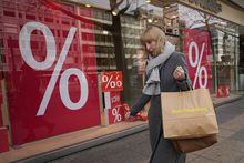 FILE - A woman walks with purchases past a store in Berlin, Germany, Friday, April 1, 2022. The European economy scraped out meager growth of 0.1% in the first three months of the year, barely gaining momentum after dodging a winter recession as challenges persist from inflation that corrodes people’s willingness to spend. (AP Photo/Pavel Golovkin, File)