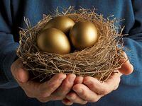 Senior Citizen holding three golden eggs in a bird's nest.
