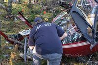A TSB investigator examines the wreckage of a Robinson R44 helicopter, near Thorburn Lake, N.L., in an undated handout photo.