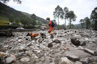 In this photo released by Xinhua News Agency, a rescue worker and dog search through the aftermath of floods in Shadai Village, Qingshan Township of Datong Hui and Tu Autonomous County in northwest China's Qinghai Province on Thursday, Aug. 18, 2022. A sudden rainstorm in western China triggered a landslide that diverted a river and caused flash flooding in populated areas, killing some and leaving others missing, Chinese state media said Thursday. (Zhang Hongxiang/Xinhua via AP)