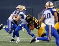 Winnipeg Blue Bombers quarterback Zach Collaros (8) gets sacked by Hamilton Tiger-Cats' Dylan Wynn (98) during the first half of CFL action in Winnipeg, Friday, June 24, 2022.    THE CANADIAN PRESS/John Woods