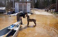 President and founder of Save A Dog Network, Katie Powell gets a kiss from a dog after bringing bags of dog food by canoe to stranded homes during flooding in Peguis First Nation, Man., Wednesday, May 4, 2022. Dozens of experts advising the government on the best way to adapt to the reality of climate change say we need to do more to prepare infrastructure for the threats of extreme weather and get faster to help Canadians recover when their lives and livelihoods are threatened by floods, fires and major storms.THE CANADIAN PRESS/David Lipnowski