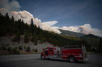 A man sits in a fire truck as the Lytton Creek wildfire burns in the mountains near Lytton, B.C., on Sunday, August 15, 2021. Cooler temperatures, spring rains and fewer lightning strikes across British Columbia are contributing to a slow start to the wildfire season. THE CANADIAN PRESS/Darryl Dyck