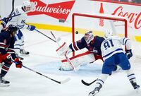 Toronto Maple Leafs' John Tavares (91) scores on Winnipeg Jets goaltender Connor Hellebuyck (37) during first period NHL action in Winnipeg, Saturday, October 22, 2022. THE CANADIAN PRESS/John Woods
