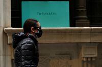 FILE PHOTO: A man passes by the closed Tiffany & Co store on Wall St. in the financial district of New York City, U.S., March 17, 2020. REUTERS/Lucas Jackson/File Photo