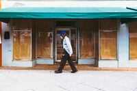A man walks past a boarded-up business on Nov. 5, 2020, in West Palm Beach, Fla.