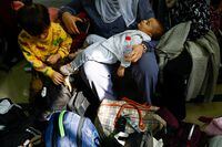 A baby is held as Palestinians with foreign passports wait for permission to leave Gaza.