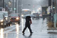 A pedestrian shields themselves from rain and wind during a rainfall warning in Halifax on Thursday, January 26, 2023. The East Coast's whipsaws between freeze and thaw has complicated life for the Canada Winter Games, as athletes and organizations adapt to what climate scientists say is the new reality of less snow.THE CANADIAN PRESS/Darren Calabrese