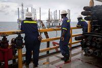FILE PHOTO: Crew members look over idle oil rigs in the Gulf of Mexico near Port Fourchon, Louisiana August 11, 2010. REUTERS/Lee Celano/File Photo