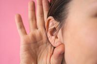 Close-up of a girl holding her hand next to her ear. The concept of chatter, gossip, news or secrets.