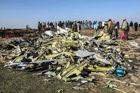 In this file photo taken on March 11, 2019, people stand near collected debris at the crash site of an Ethiopian Airlines flight, near Bishoftu, Ethiopia.