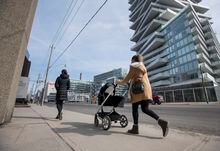 A woman pushes a stroller along Queens Quay East on Mar 10 2021. With more condominium developments being built along the Toronto waterfront, access to school could become a problem for families living there. Fred Lum/The Globe and Mail