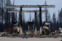 A security worker walks near a burned down gas station after the Bush Creek wildfire destroyed dozens of homes in multiple rural communities including Scotch Creek, Lee Creek and Celista in the North Shuswap Lake region of British Columbia, Canada. August 23, 2023 REUTERS/Jesse Winter