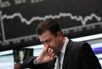A trader reacts at his desk in front of the DAX board at the Frankfurt stock exchange August 18, 2011.
