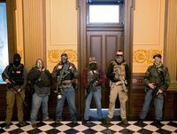 FILE PHOTO: A militia group with no political affiliation from Michigan, including Joseph Morrison (3rd R), Paul Bellar (2nd R) and Pete Musico (R) who were charged for their involvement in a plot to kidnap Michigan Governor Gretchen Whitmer, attack the state capitol building and incite violence, stand in front of the governor's office after protesters occupied the state capitol building during a vote to approve the extension of Whitmer's emergency declaration/stay-at-home order due to the coronavirus disease (COVID-19) outbreak, in Lansing, Michigan, U.S. April 30, 2020. REUTERS/Seth Herald/File Photo