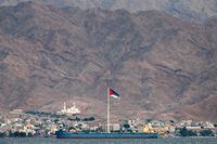 (FILES) This file picture taken on November 19, 2021 from Israel's southern Red Sea port and resort city of Eilat shows a view of the Flag of the Arab Revolt (top to bottom: black, green, and white stripes with a red chevron) flying in Jordan's nearby coastal city of Aqaba. - Israeli and Palestinian representatives held a meeting in the Red Sea resort of Aqaba on February 26, according to Jordanian state broadcaster al-Mamlaka, "the first of its kind in years" with regional and international participation to address "the situation in the Palestinian territories". (Photo by AHMAD GHARABLI / AFP) (Photo by AHMAD GHARABLI/AFP via Getty Images)