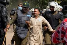 Riot police officers detain a supporter of former Prime Minister Imran Khan during clashes, in Lahore, Pakistan, Wednesday, March 15, 2023. Supporters of Khan threw bricks at police who fought back with clubs and tear gas for a second day Wednesday after officers tried to arrest the ousted premier for failing to appear in court on graft charges.(AP Photo/K.M. Chaudary)