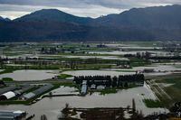 A helicopter flies over flooded farmland in Abbotsford, B.C., on Wednesday, December 1, 2021. The City of Abbotsford is getting a funding boost from the B.C. government to help ensure its drinking water system will withstand extreme weather and climate-related disasters. THE CANADIAN PRESS/Darryl Dyck