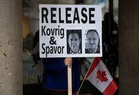 A young man holds a sign bearing photographs of Michael Kovrig and Michael Spavor, who have been detained in China for more than a year, outside B.C. Supreme Court where Huawei chief financial officer Meng Wanzhou was attending a hearing, in Vancouver, on Tuesday January 21, 2020. THE CANADIAN PRESS/Darryl Dyck