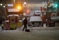 A protester shovels snow in front of parked semi-trailer and pickup trucks on Rideau Street, on the 21st day of a protest against COVID-19 measures that has grown into a broader anti-government protest, in Ottawa, on Thursday, Feb. 17, 2022. The commission investigating the government's use of the federal Emergencies Act last winter will hear this week from the protesters who organized the occupation of downtown Ottawa. THE CANADIAN PRESS/Justin Tang