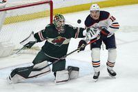 Minnesota Wild goalie Cam Talbot, left, deflects a shot in front of Edmonton Oilers' Zach Hyman in the second period of an NHL hockey game, Tuesday, April 12, 2022, in St. Paul, Minn. (AP Photo/Jim Mone)