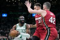 Boston Celtics guard Jaylen Brown (7) drives to the basket against Miami Heat forward Kevin Love (42) and guard Max Strus (31) in the second half of Game 1 of the NBA basketball Eastern Conference finals playoff series in Boston, Wednesday, May 17, 2023. (AP Photo/Charles Krupa)