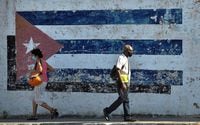 People walk near a mural depicting a Cuban flag in Havana, on April 16, 2021. The 8th Congress of the Cuban Communist Party starting Friday will end over six decades of the government of Fidel and Raul Castro, giving way to a new generation.